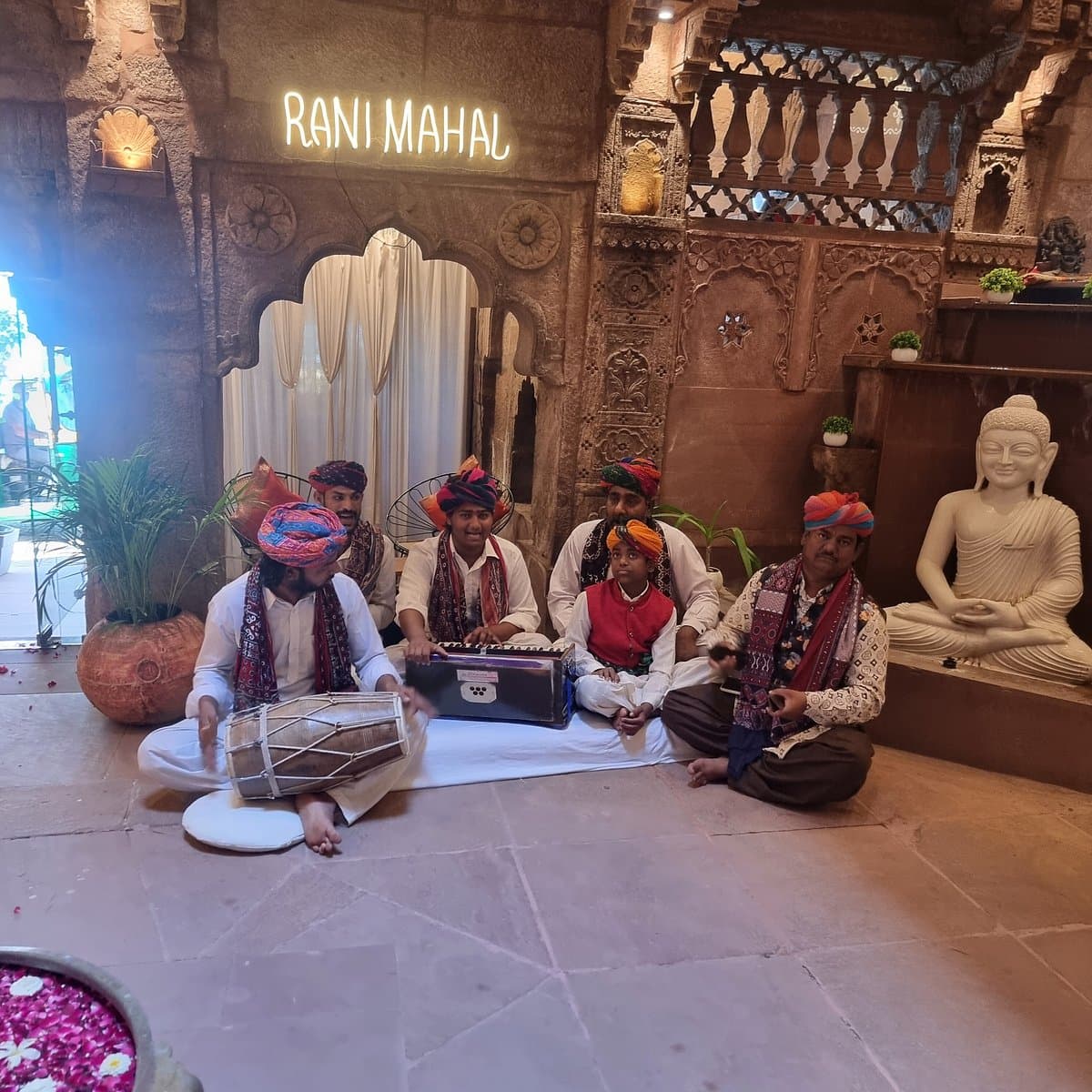 Folk musicians performing beneath the Rani Mahal signage